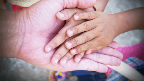 Adult hand holding 2 child hands