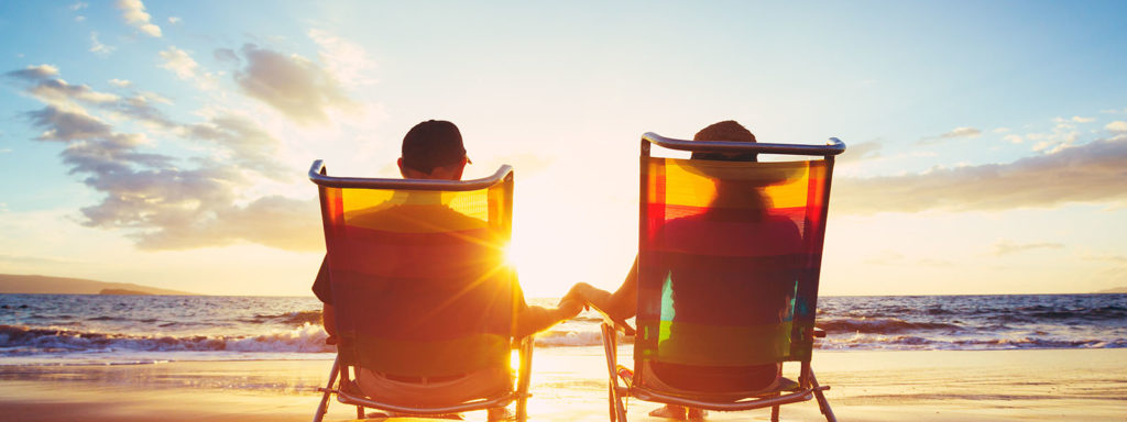 A couple holding hands on the beach. Retirement planning is easy at Trajan Wealth.