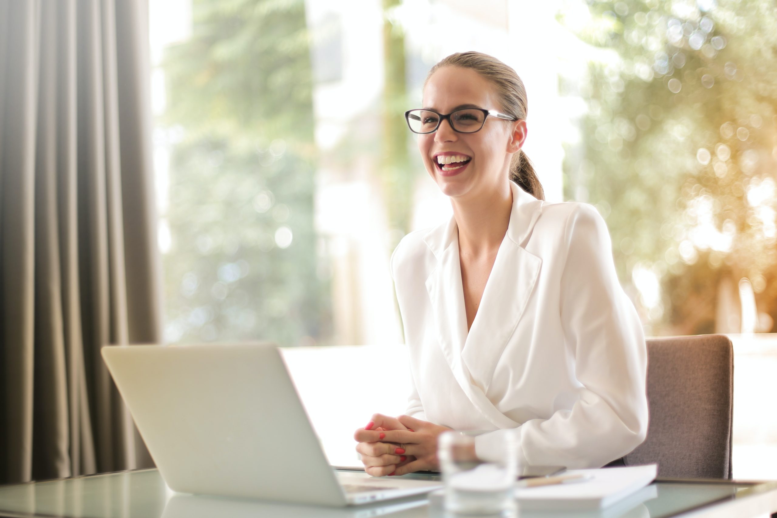 Woman smiling sitting at desk with laptop