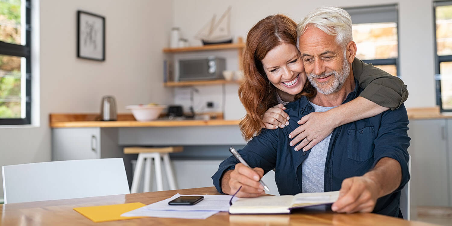 Mature couple embraced as they look at paperwork