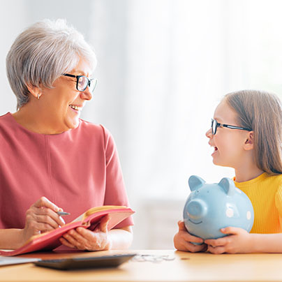 Woman and child sitting at desk with a piggy bank 