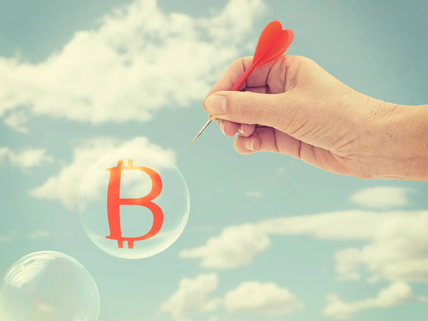 Hand popping bubble with Bitcoin symbol